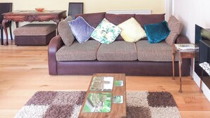 A living room with a sofa, a coffee table, a side table, a mirror, and framed pictures on the wall. - 1 bedroom accommodation in Malvern (Malvern)