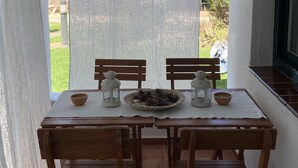 A wooden table with four chairs, two white lanterns, and a woven basket with pinecones.