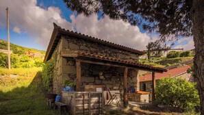 A stone building with a tiled roof, a wooden bench, and a table outside. - Lemon Tree at Terrus Winery (Barrô, Viseu)