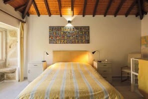 A bedroom with a bed, bedside tables, a lamp, a chair, a wall-mounted artwork, and a window with curtains.