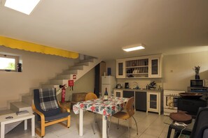 A compact living space with a dining table, chairs, a sofa, a kitchen area, and a staircase.