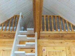 A wooden staircase with a handrail leading to a lofted area with a sloped ceiling. - Etelätuuli by Interhome (Manamansalo)