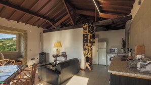 A modern kitchen with a microwave, stove, and sink. There is a dining area with a table and chairs. - River View at Terrus Winery (Barrô, Viseu)
