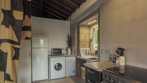 A compact kitchen with a washing machine, microwave, and stove. - River View at Terrus Winery (Barrô, Viseu)