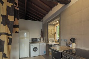 A compact kitchen with a washing machine, microwave, and stove.