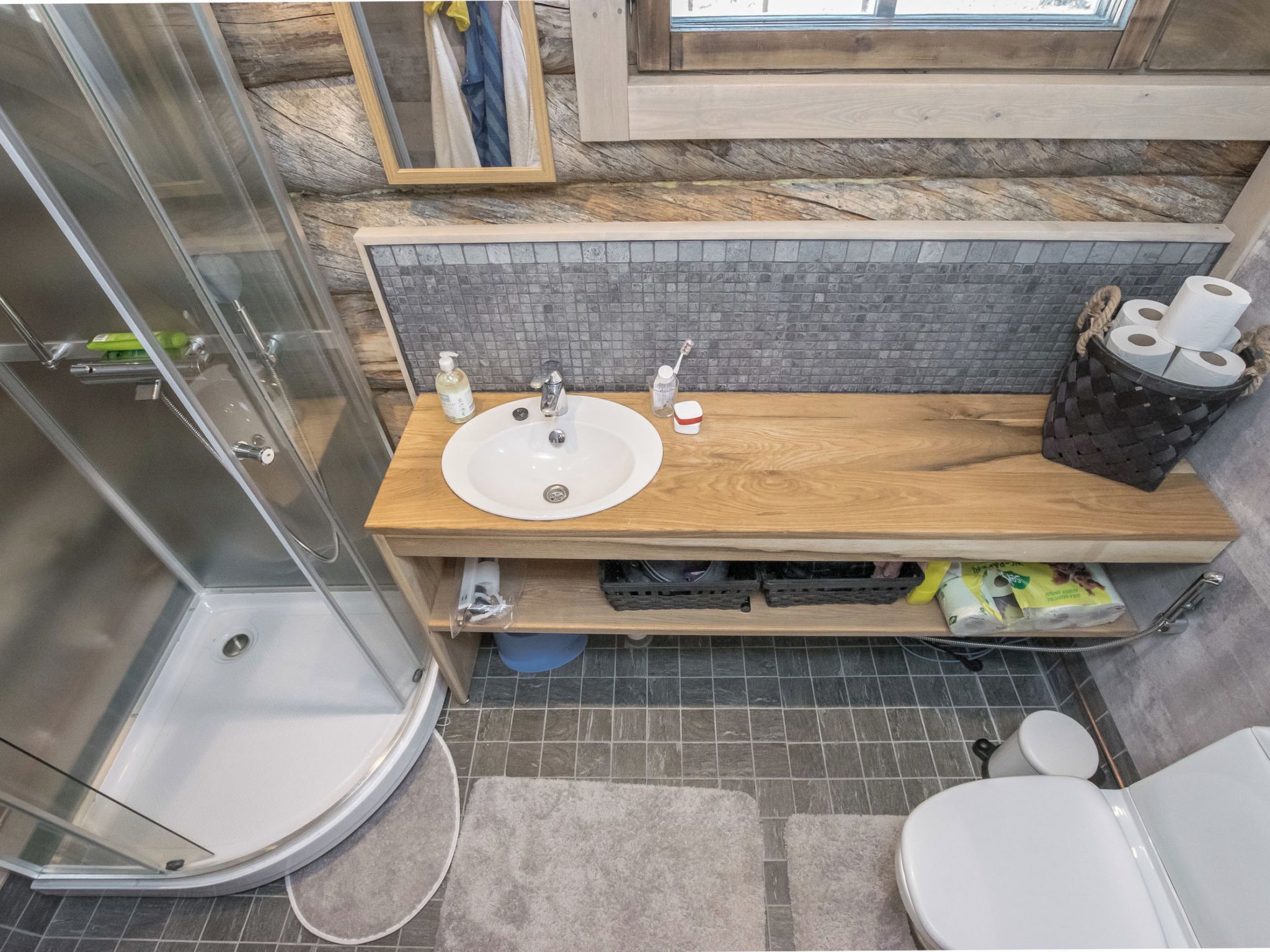 A modern bathroom with a glass shower enclosure, a wooden vanity with a sink, and a toilet.