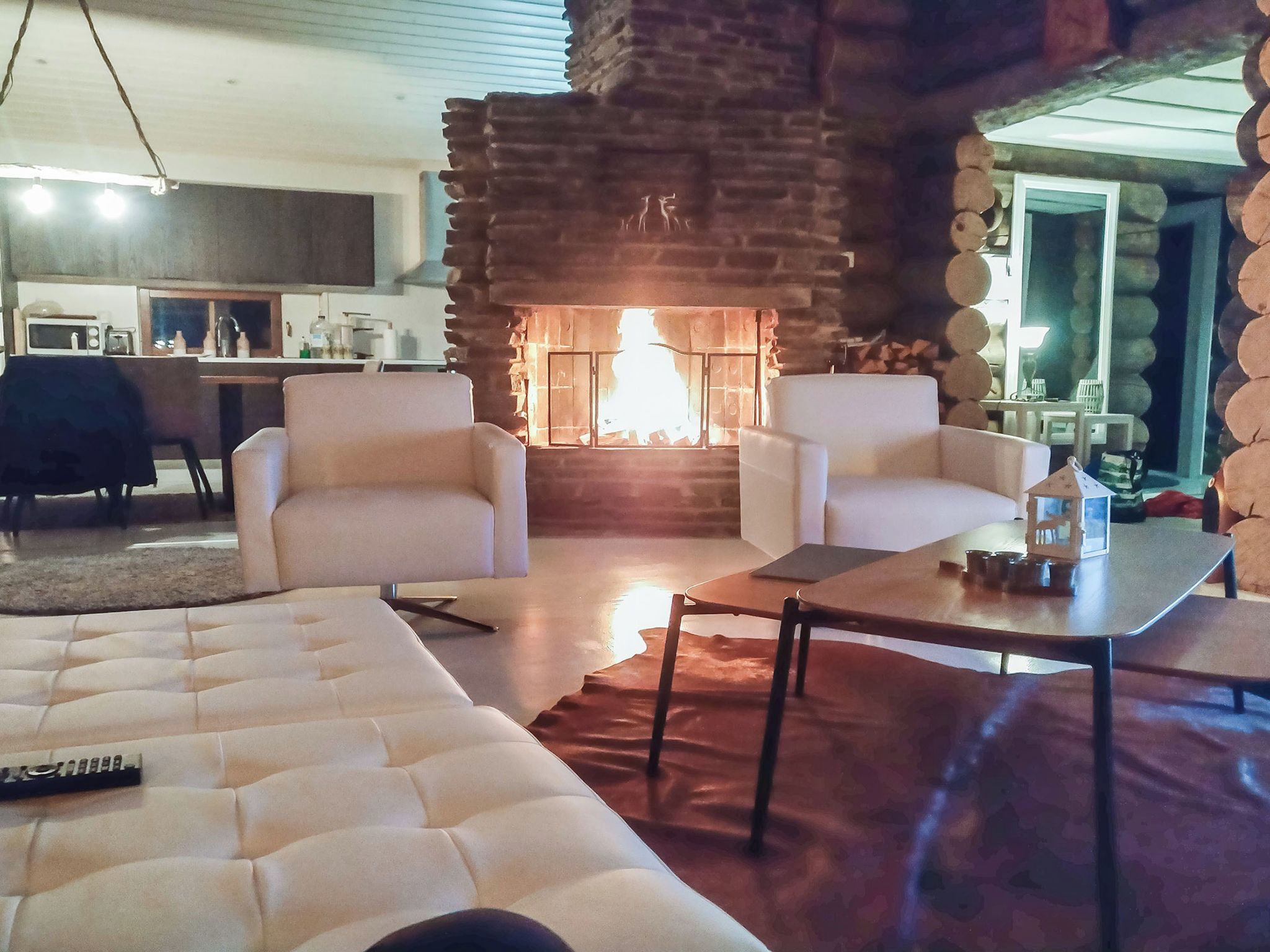 Una sala de estar con chimenea, un sofá, una mesa de centro y una cocina al fondo.