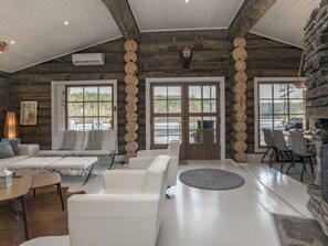 A spacious living area with a fireplace, large windows, and a stone wall. - Villa moose by Interhome (Mikkeli)