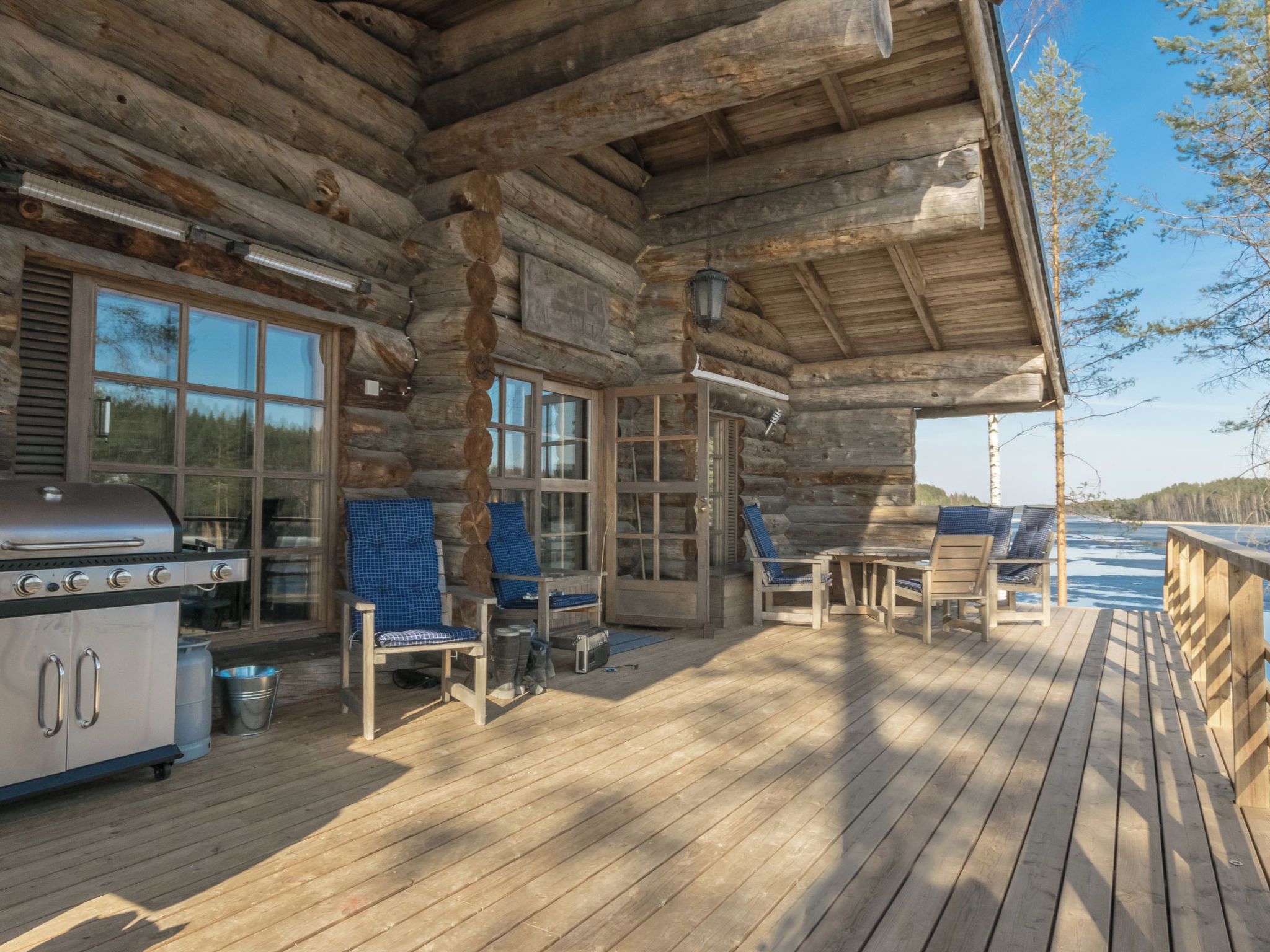 Une terrasse en bois avec des sièges d’extérieur, un barbecue et une vue sur un plan d’eau.