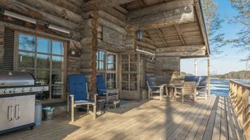 Une terrasse en bois avec des sièges d’extérieur, un barbecue et une vue sur un plan d’eau.