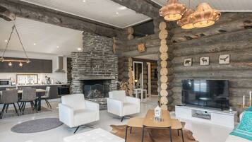 Un salon moderne avec une cheminée en pierre, des meubles blancs et un téléviseur.