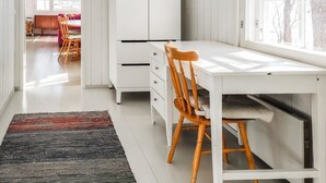 Une pièce lumineuse et moderne, avec un bureau blanc, des chaises en bois et une grande fenêtre.