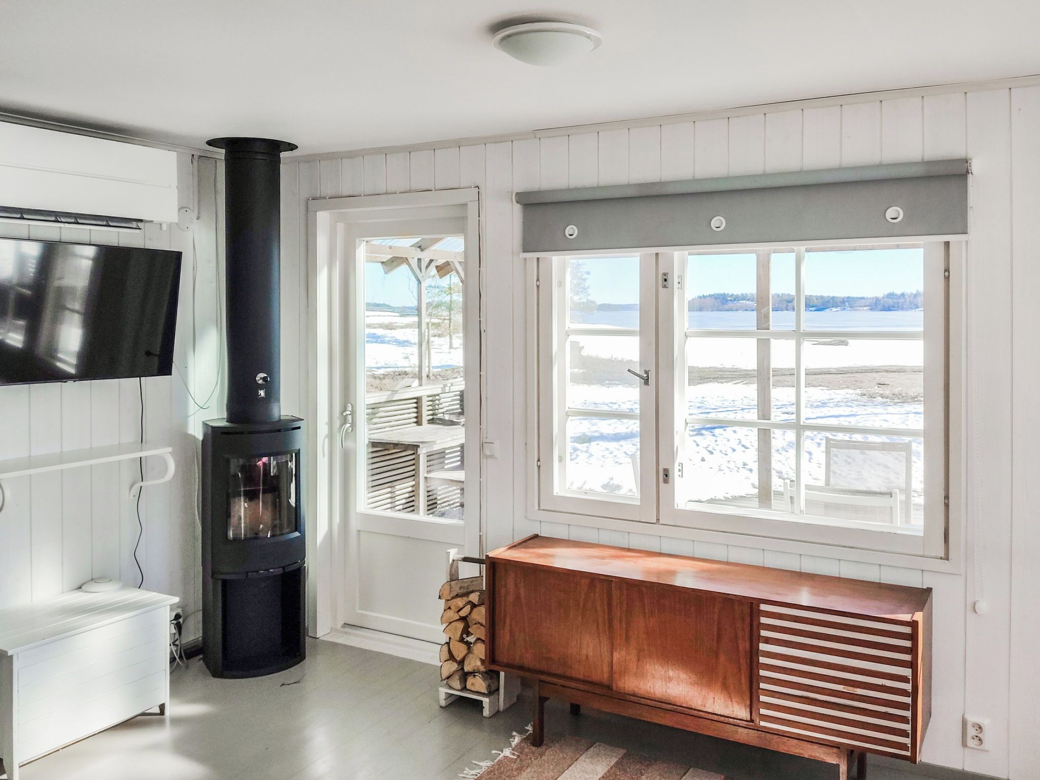 A room with a fireplace, a television, and a window with a view of a snowy landscape.
