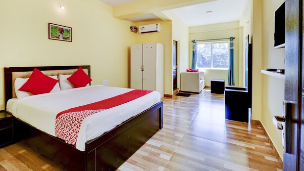 A hotel room with a large bed, a wardrobe, a television, and a window with curtains. - Gaurika Residency Lodging and Boarding (Udupi)
