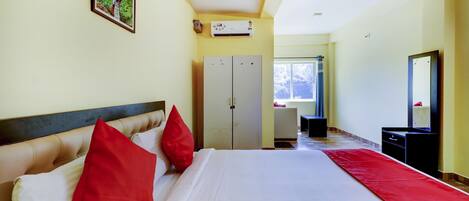A hotel room with a bed, a wardrobe, a mirror, and a window.