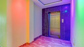 A hallway with a marble wall and an elevator. - Gaurika Residency Lodging and Boarding (Udupi)