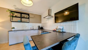 Una cocina moderna con una isla central, estantes empotrados y un televisor de pantalla plana.