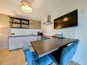Una cucina moderna con isola centrale, scaffalature integrate e una TV a schermo piatto.