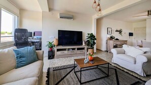Una sala de estar moderna con sofá, mesa de centro, televisor y plantas decorativas.