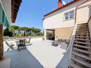 Un'area patio coperta con mobili da esterno, un muro in pietra e una scala che conduce a un livello superiore.