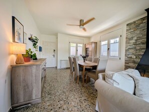 A spacious living area with a dining table, chairs, a sofa, a fireplace, and a ceiling fan.