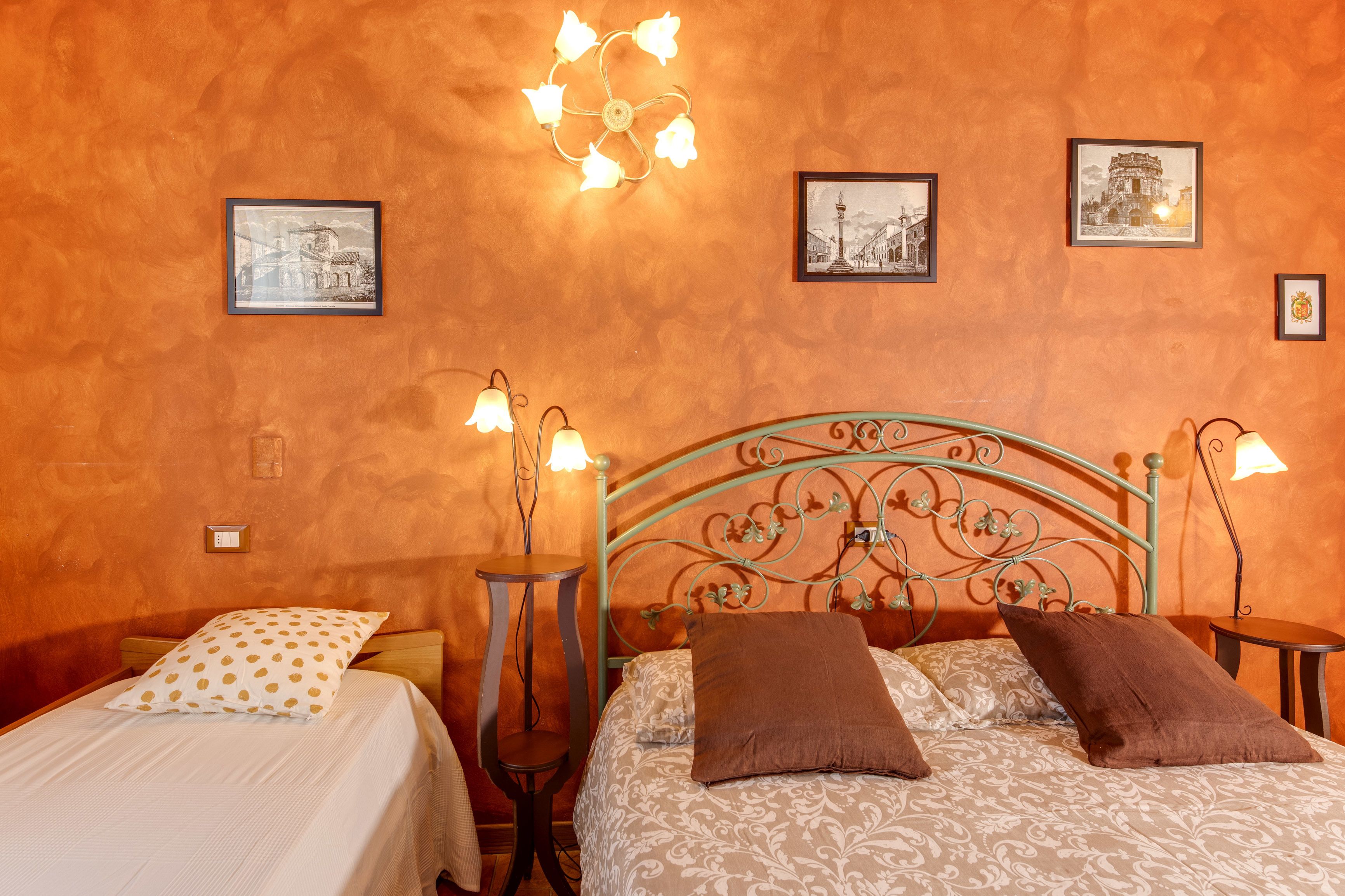 Camera da letto con un letto, due comodini, una lampada a parete e quadri incorniciati.