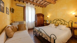 Ein Schlafzimmer mit Holzboden, einem Bett mit weißer Bettwäsche, einem Holzschrank und einer Heizung.
