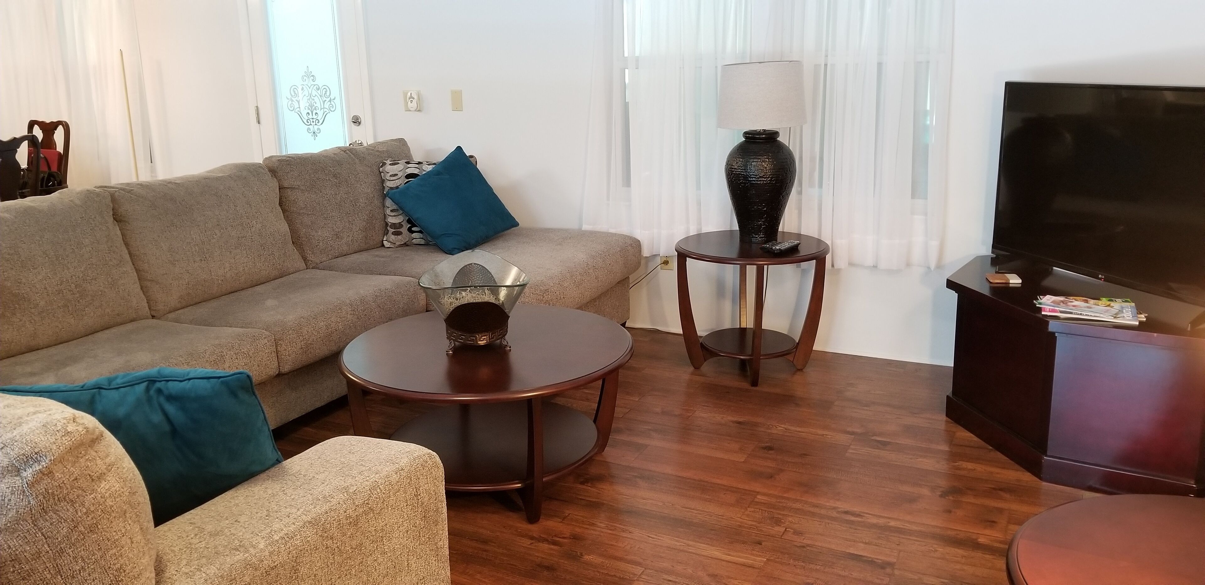 A living room with a sofa, coffee table, side tables, a lamp, and a TV.