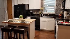 Eine moderne Küche mit weißen Schränken, einem schwarzen Kühlschrank und einer Holzinsel mit Hockern.