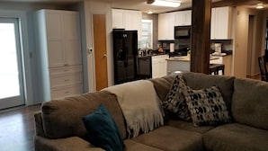 Ein modernes Wohnzimmer mit einer Couch, einem Couchtisch und einer Küche im Hintergrund.