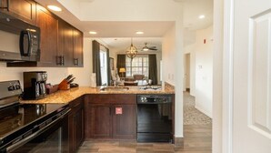 A modern kitchen with dark wood cabinets, a granite countertop, and stainless steel appliances.