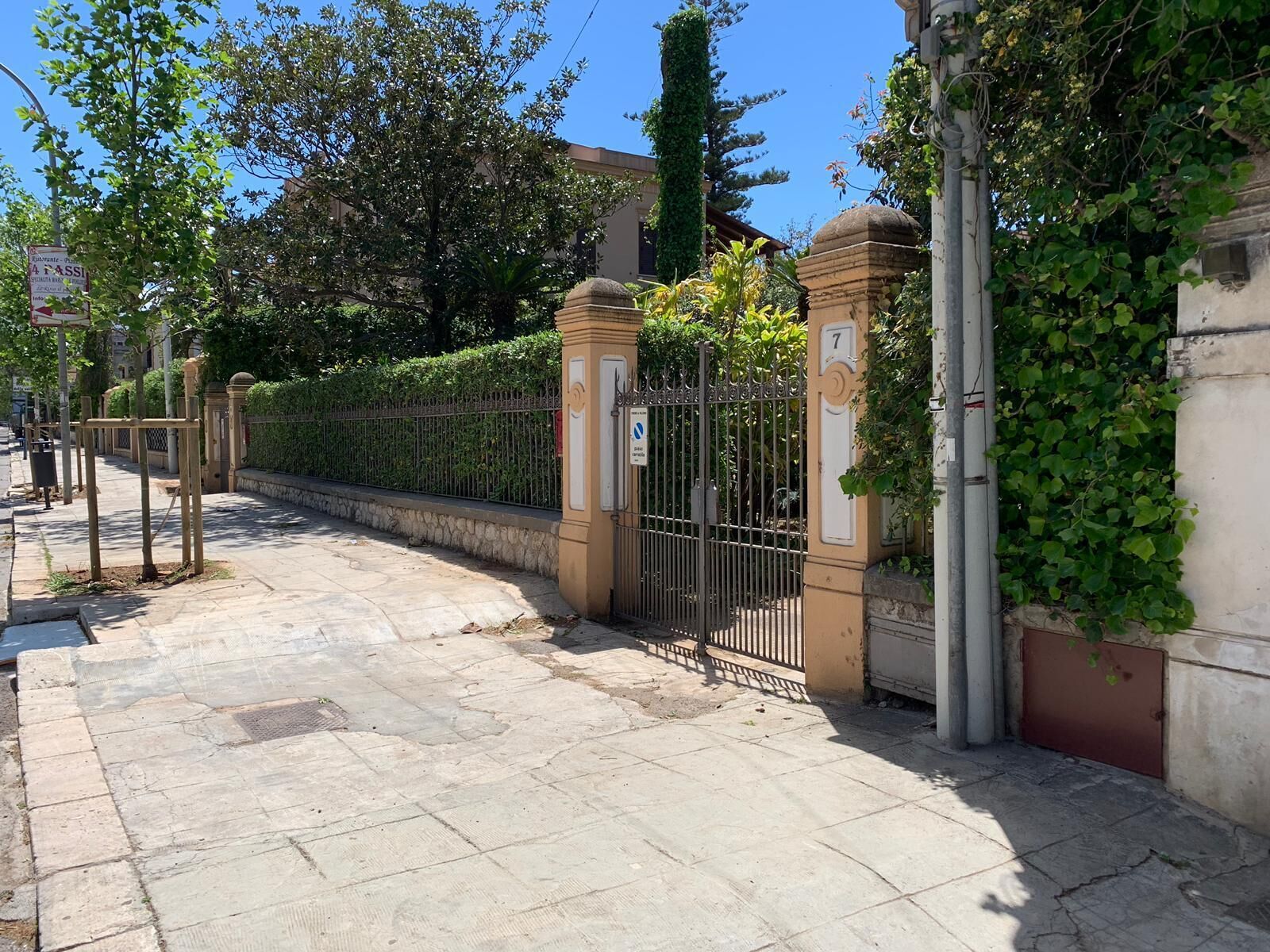 Una entrada protegida por una verja metálica y un sendero de piedra que conduce a un edificio.