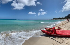 A beach with a red boat on the sand and a person in the background. - Mondello Beach just 90 meters from the sea. Apartment in a Liberty style villa (Palermo)