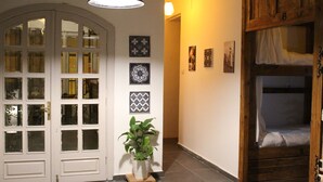 A hallway with a white door, a potted plant, and a bunk bed. - The Cabin Hostel (Amman)