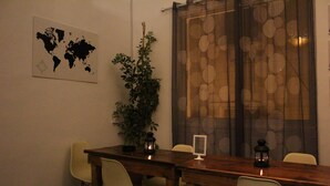 A dining area with a wooden table, four chairs, a world map on the wall, a potted plant, and a decorative curtain. - The Cabin Hostel (Amman)