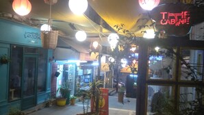 An indoor corridor with hanging lights, potted plants, and a sign reading "THE CABINE". - The Cabin Hostel (Amman)