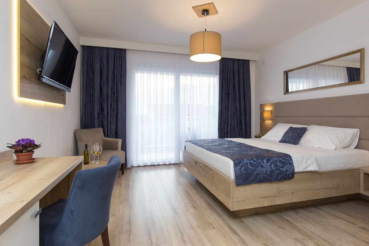 A hotel room with a bed, a desk, a chair, a television, and a window with curtains.