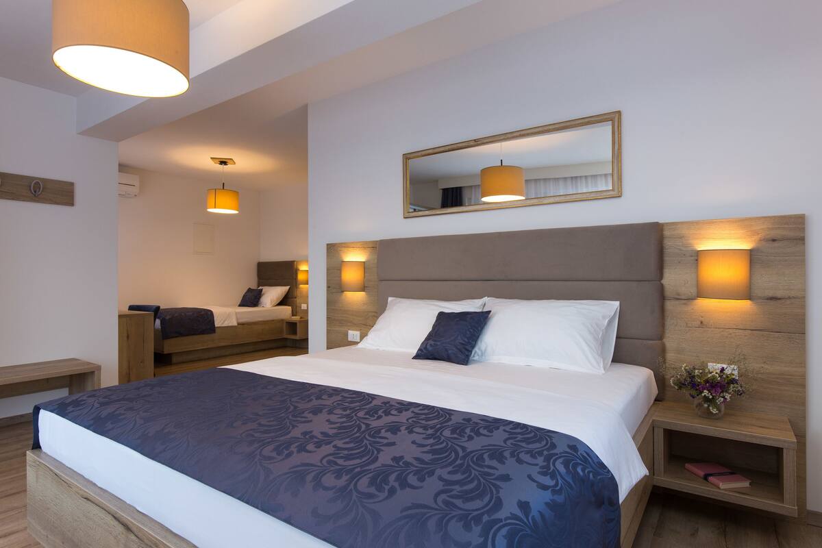 A modern hotel room with a large bed, bedside tables, a mirror, and ambient lighting.