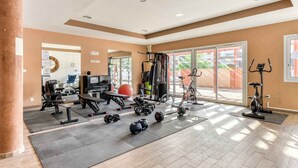 Une salle de sport spacieuse, dotée de divers appareils d’exercice, de grandes fenêtres et d’un mur entièrement recouvert de miroirs.