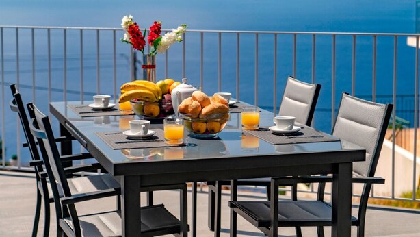 A dining table with breakfast items and a view of the sea. - Beautiful Modern Villa in Calheta – CalhetaScape (Estreito da Calheta)