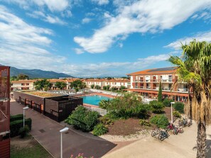 Un hotel con piscina en la azotea, asientos exteriores y vistas a las montañas.