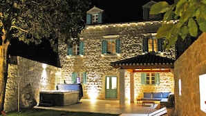 Ein Steinhaus mit überdachter Terrasse, Sitzgelegenheiten im Freien und einem kleinen Tisch.