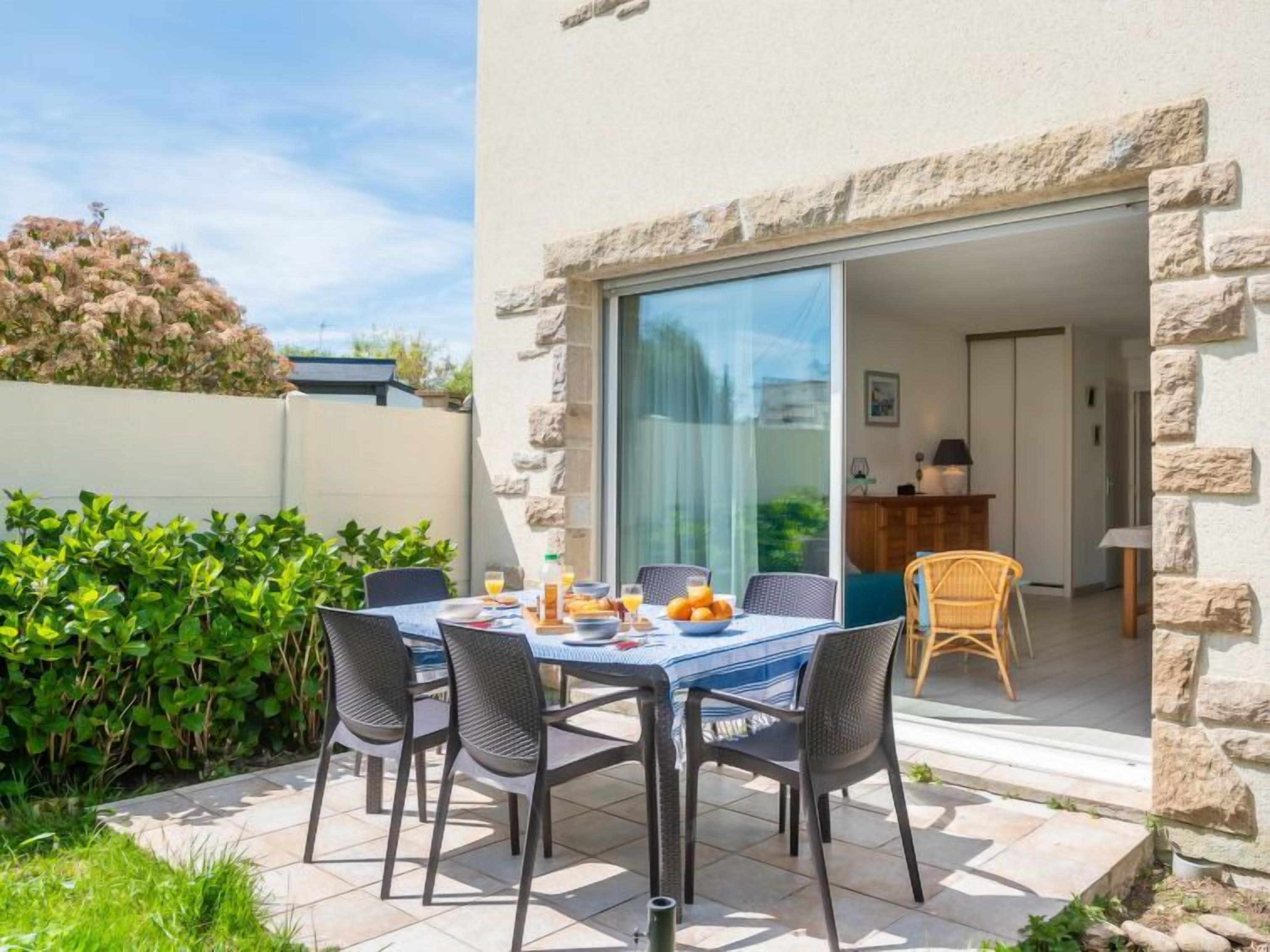 A patio with a table set for breakfast, surrounded by stone walls and greenery.