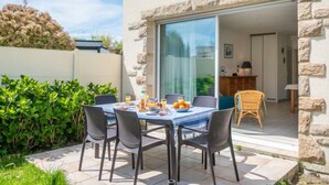Un patio con una mesa lista para el desayuno, rodeado de muros de piedra y follaje.