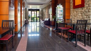 A hotel lobby with a reception desk, seating area, and a stone wall.