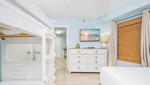 A bedroom with a bed, a dresser, a painting, and a window with curtains.