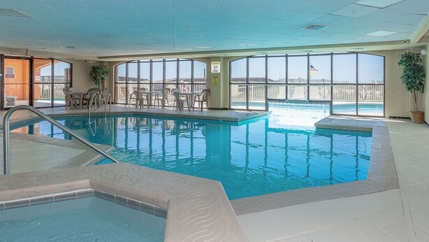 An indoor swimming pool with clear views of the surrounding area through large windows.