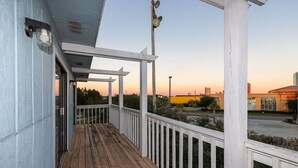A wooden deck with a white railing, overlooking a parking area and a building with a yellow facade. - Fantastic 2BR Condo - Romar Village 622 (Orange Beach)