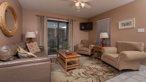 A living room with a sofa, two armchairs, a coffee table, and a television on the wall. - Fantastic 2BR Condo - Romar Village 622 (Orange Beach)
