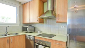 Uma cozinha moderna com armários de madeira, eletrodomésticos de aço inoxidável e uma janela que proporciona iluminação natural.